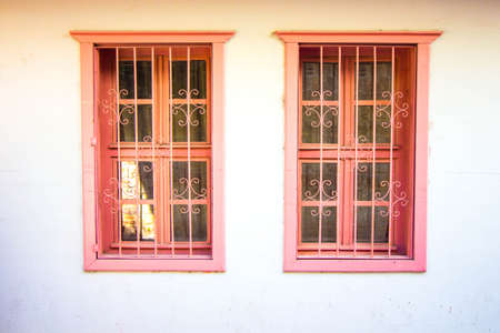 Antique windows in a pink hue. Protective metal bars are installed on the windows.の写真素材