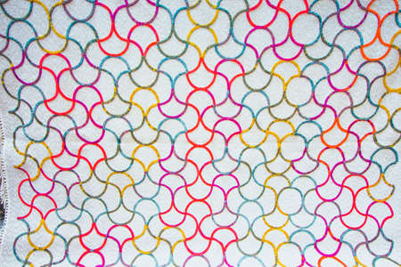 Beautiful white fabric with colorful patterns. Patterns of bright colors intertwined in red, blue...