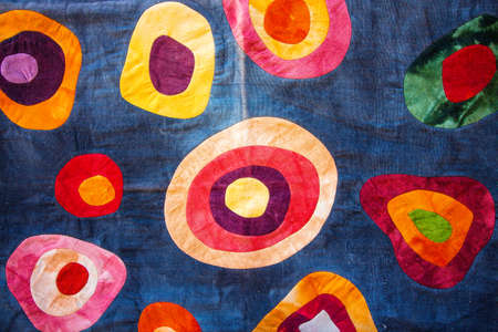 Bright and colorful patterns on the fabric. The patterns are in the shape of circles, while the weave itself has a blue tint.の写真素材