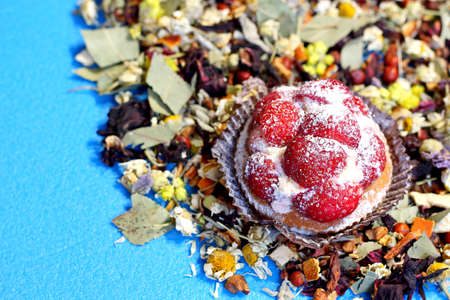 Tasty and fresh cake with strawberries. Around the cake, various dried herbs for brewing in tea. Cake on a neutral background in blue.の写真素材