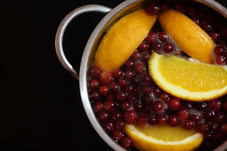 Stewed oranges and cranberries. Stewed fruit is on the stove in the pan, it has just been cooked and ready to eat. Fresh fruit and berry compote is very healthy and rich in vitamins.の写真素材
