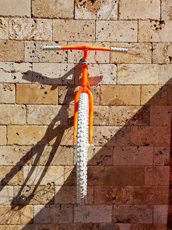 Orange bike on a stone wall. Beautiful decoration of the stone wall of the building.の写真素材