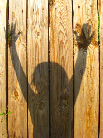 shadows of teen's hand raising up on the wooden fenceの写真素材