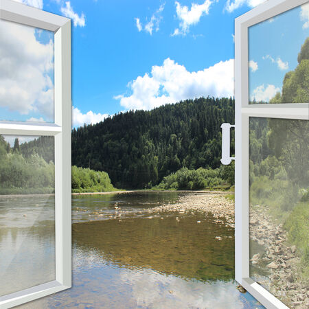 opened window overlooking the picturesque river and mountainsの写真素材