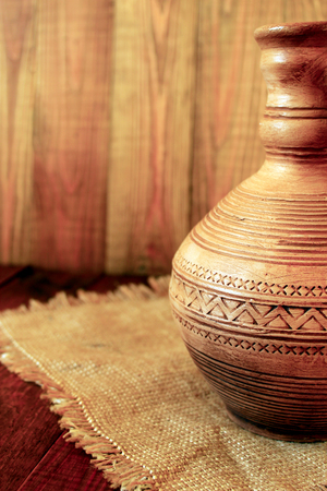 Decanter ceramic brown on the sacking. Old crockery on the decorative backgroundの写真素材