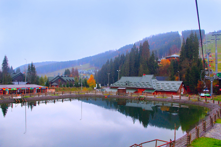Picturesque lake and tourist houses in ukrainian ski Bukovel. Landscape with mountain lake in resort town. Mountains in resort villageのeditorial素材