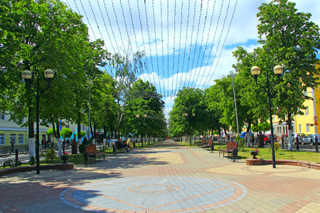 Street of Belarusian city of Gomel with benches trees and hanging garlands. People resting in park with benches and garlands. People relax in city. Beautiful city park. Place for restのeditorial素材