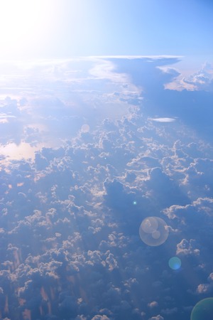 Wonderful view from window of plane to sun shining over clouds. Clouds illuminated by rays of sun. Beautiful white clouds with sunny rays. Landscape with sun and sky. Heaven panoramaの写真素材