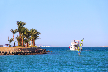 View of tropical island with palm trees and promenade ship on sea. Paradise island in Red sea. Tropical resort. Vacations concept. Marine panorama with beach palm trees and seaのeditorial素材