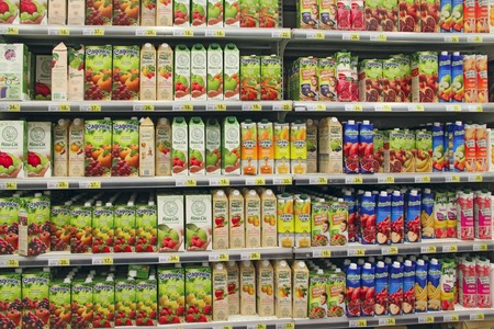 Wide range of juices on supermarket shelves. Natural juices on shelves of shop. Different fruit juices on shelves in supermarket. Various juice in paper packageのeditorial素材