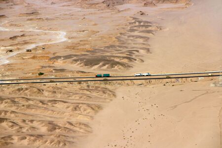Beautiful view onto asphalt road in wild sandy lands of desert. Aerial scenery view of highway passing through desert. Drone shot from above of desert landscape with highway.の写真素材