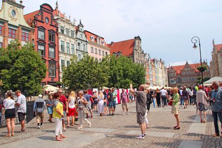 Tourists stroll and take pictures of Gdansk. Many tourists walk around Gdansk. Beautiful tourist Polish city of Gdansk. Group of Europian tourists during journeyのeditorial素材