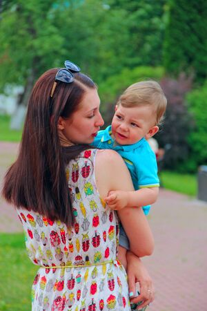 Young mother looking at son. Motherhood. Family relationships. Little son in arms of mom. Young woman holding little boy on handsのeditorial素材