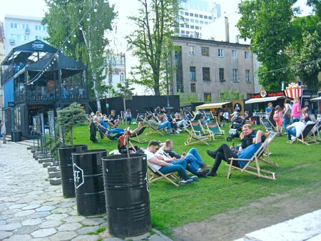 Tourists rest sitting on folding chairs on the lawn. Tourists relax in a city park sitting on chairs on green grass.のeditorial素材