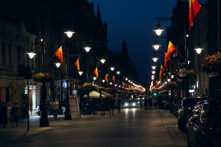 Central street of Lodz Piotrkowska decorated by flags in evening. Main touristic street of Lodz...