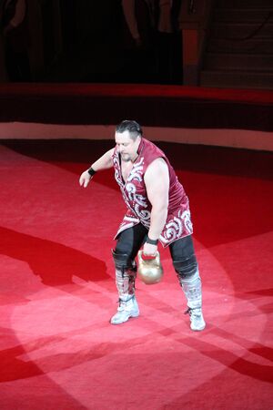 Strong man showing tricks with weights on arena of circus. Tricks on circus arenaのeditorial素材