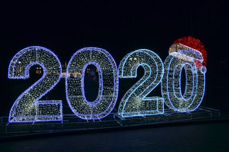Beautiful Christmas figures 2020 made of colored garlands. Large glowing numbers 2020 in city park....