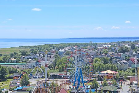 ferris wheel on blue sky background. Panorama of Wladyslawowo town from above with street many houses and ferris wheel. Panorama of resort Polish town with Ferris wheel and view of Baltic Seaの写真素材