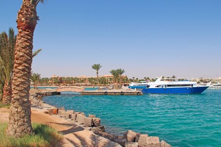 city harbor with moored boats ships and cruise liners. Ships and liners in port. liner is moored on pier on Red sea. Sailing boats in harbor. Modern water transportのeditorial素材