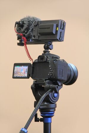 Camera mounted on the tripod ready for shooting. Professional camera with picture on display in...