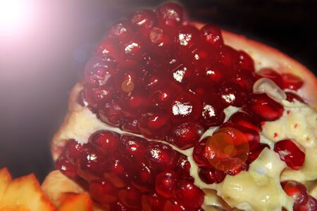 Ripe seeds of pomegranate in light rays close up. delicious fruits. Red seeds of pomegranate. delicious fruits. Useful food. Health care. tropical fruitsの写真素材