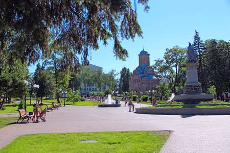 Beautiful city park with promenade path benches fountains and big green trees. City park in summer....