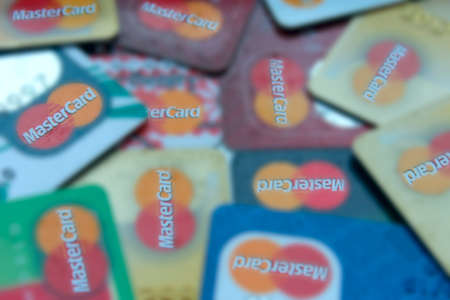 some credit cards with Mastercard brand logo blurred. Blurred close up of many Mastercard credit cards. Plastic bank cards of Mastercard. International payment systemsのeditorial素材