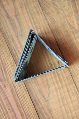 Hundred dollar notes on wooden boards. Hundred dollar bills folded in triangular shape. Money in...
