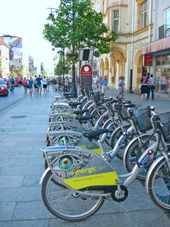 View of city street with many bicycles. Bicycles parked in rental parking lot. Bicycles for rent in city. Bicycle rental in Warsaw. Green city transport. Street transportationのeditorial素材
