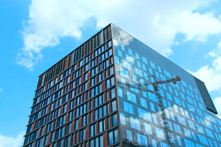 Construction crane reflecting in glasses of building during construction of multi-storey building....