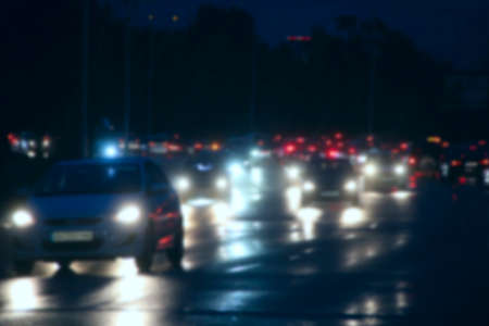 Automobiles with headlights and lights on in night city blurred. Blur image with traffic jam in city. Cars with headlights on. Traffic jam in evening city. Busy traffic jam with cars in evening cityの写真素材