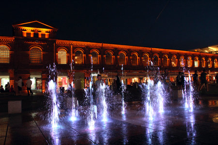 Children play with night fountains in the city of Lodz. Beautiful evening fountains. People have a rest near beautiful illuminated buildings at night. Architecture with beautiful night illuminationの写真素材