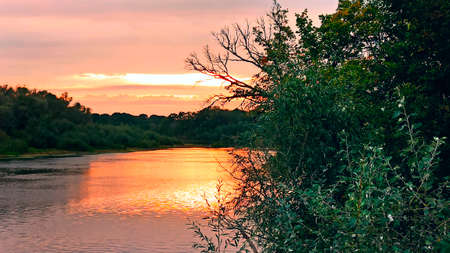 Sunny rays leaving with decline. Evening landscape. Beautiful summer decline above lake. Beautiful blazing sunset landscape above river and orange sky in evening. Amazing autumn sunsetの写真素材