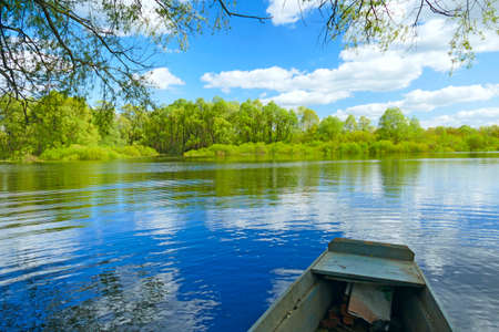 Countryside transport at river during spring flood. Wooden fishing boat standing on river in early...