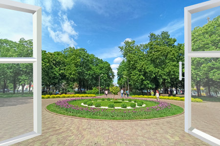 Open window to city park with flower beds and flowers. View of a flower bed in the city park. Spring...