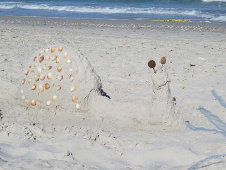 Figures of sand and shells on the beach against the sea. Tunisia