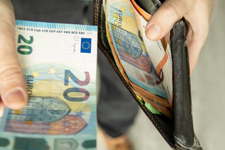 Hand taking euro banknotes from a wallet. Concept of personal finance, budgeting, spending and money management.の写真素材