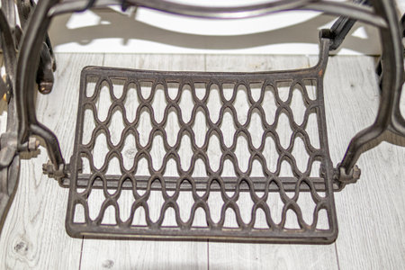 Close-up of vintage metal chair footrest with geometric pattern on light wooden floor. homeの写真素材