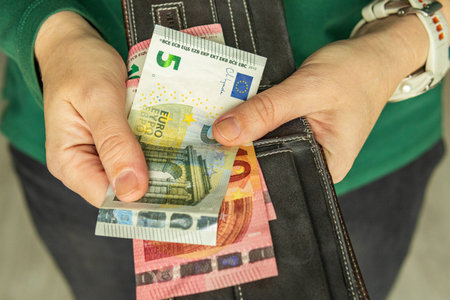 Hands pulling euro banknotes from a wallet, representing cash withdrawal, budgeting, spending, and personal finance management.の写真素材