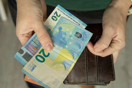 Hands holding euro banknotes and a leather wallet. Close up of money and personal finance concept...