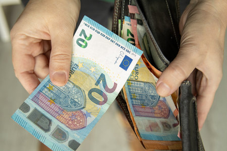 Hand taking euro banknotes from a wallet. Concept of personal finance, budgeting, controlling expenses and managing daily money.の写真素材