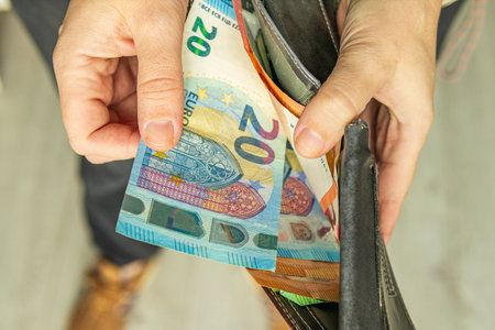 Hand taking euro banknotes out of a wallet. Concept of personal finance, budgeting, cash spending, savings, and everyday money management.の写真素材