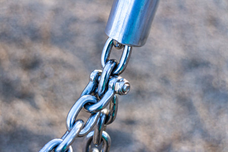 Close-up of metal chain connected to a steel fitting. Industrial fastening detail showing strength,...