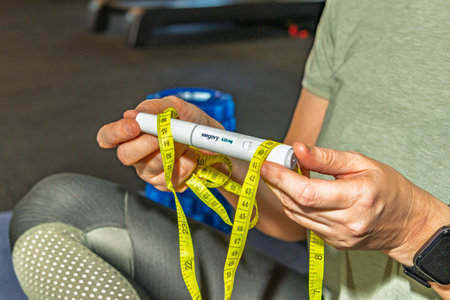 Wroclaw, Poland. January 2026.A person holding a Wegovy injection pen wrapped with a measuring tape, illustrating the real-life use of prescription medication for medical weight loss and obesity management.のeditorial素材