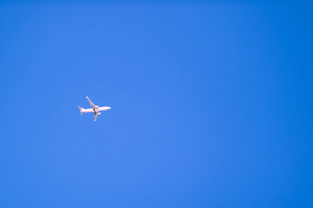 Airplane flying in clear blue sky with copy space. Minimal travel, aviation and freedom concept,...