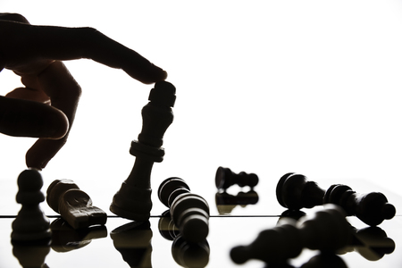 Hand tilting the figure of the king on the chessboard.Focus on the figure of King.Soft focus