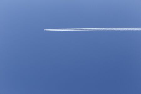 Trace of an airplane flying in the blue skyの写真素材
