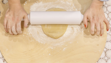 Woman rolls a cake on a wooden cutting board