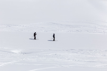 Skiers go down the mountain roadの写真素材
