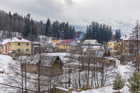 Snow-covered houses in the village of Bakuriani on a background of mountainsの写真素材